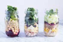 Different layered salads in glass jars — Stock Photo