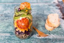 Quinoa salad in a glass jar with red cabbage, chickpeas, avocado, blood orange and cress — Stock Photo
