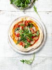 Тонка піца земної кори з шпинахом, салямі і горгонцолою зверху з свіжими аругулами. — стокове фото