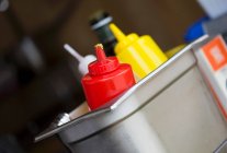 Ketchup, mustard and seasoning sauces in a metal container in a restaurant — Stock Photo