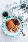 Duck breast with cranberry sauce on a plate in the snow at Christmas — Stock Photo