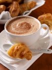 A cup of cappuccino coffee and croissants — Stock Photo
