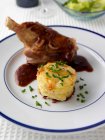 Lamb shank with potatoes tower and sauce on plate — Stock Photo