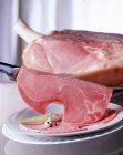 A piece of ham with a knife and sliced ham on a plate — Stock Photo