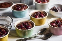 Chocolate and cherry clafoutis in colourful ramekins — Stock Photo
