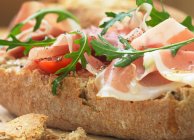 Panini with prosciutto, tomatoes and rocket leaves — Stock Photo