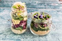 Orzo pasta salad and quinoa salad in glass jars — Stock Photo