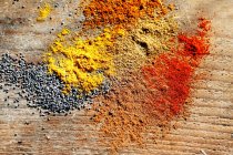 Various spices and poppyseeds on a wooden surface — Stock Photo