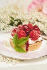 A fresh rasberry tart with a rasberry leaf with rose and hawthorn flowers — Stock Photo