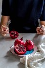 Frau hält Granatapfelkerne und Messer auf einem Holztisch — Stockfoto
