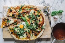 Pizza con salsa di pomodoro, uovo fritto, rucola, olive e parmigiano — Foto stock