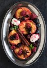 Жареные ягоды и персики со сливками из маскарпона в тарелке — стоковое фото