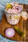 Sausage salad with red onion and gherkins in a glass on a wooden board — Stock Photo