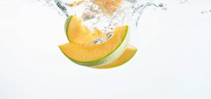 Honeydew melon falling into fresh water — Stock Photo