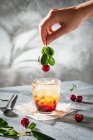 Mocktail de cereja gelada com mão segurando cereja — Fotografia de Stock