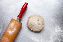 Une boule de pâte avec rouleau à pâtisserie — Photo de stock