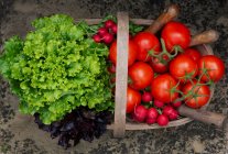 Légumes verts frais dans un bol en verre et un poivron rouge sur fond noir — Photo de stock