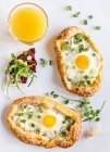 Mini pizzas with fried eggs and a glass of orange juice — Stock Photo