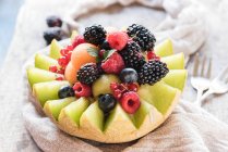 Eine halbierte Melone gefüllt mit Melonenbällchen und frischen Beeren — Stockfoto