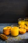 Очки свежевыжатого апельсинового сока с фруктовыми половинками и кожурой — стоковое фото