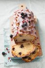 Um bolo de pão de mirtilo fatiado com gelo e pétalas de rosa secas — Fotografia de Stock