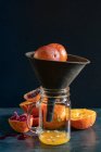 Oranges and blood oranges being juiced in hand juicer — Stock Photo