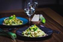 Tagliatelle with salmon and leek and drinks in glasses on table — Stock Photo