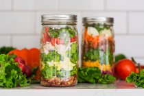 Salades en deux couches dans des bocaux en verre aux épinards, haricots, fromage et œufs — Photo de stock