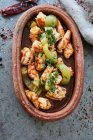 Chili prawns with herbs in rustic clay dish — Stock Photo