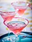 Cosmopolitan cocktails with pink sugar and ice cubes in glasses — Stock Photo