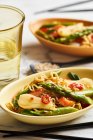 Asian noodles with green asparagus, spring onions, carrots, red peppers and sesame seeds — Stock Photo
