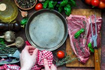 Сырой стейк с кастрюлей и различными ингредиентами — стоковое фото