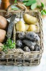 Différents types de pommes de terre dans un panier — Photo de stock