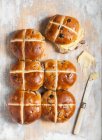 Hot cross buns avec du beurre sur un fond en bois (cuisson de Pâques, Angleterre) — Photo de stock