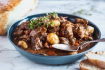 Beef Bourguignon garnished with fresh lemon thyme and served with homemade artisan bread — Stock Photo