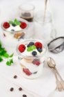 Jars of cream dessert with raspberries, blueberries, cookies and mint — Stock Photo