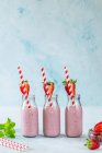 Yummy milkshake with fresh ripe strawberry on table in pink light — Stock Photo