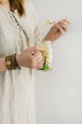 A woman in a linen dress holding a salad jar with wholegrain pasta, carrots, cauliflower and green salad leaves — Foto stock
