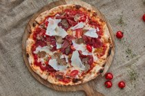 Una pizza con salsa de tomate, mozzarella, bresaola, trufas y queso parmesano - foto de stock