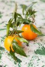 Mandarines fraîches avec feuilles sur la surface rustique — Photo de stock