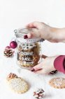 Hands holding a glass jar with decorated Christmas cookies — Stock Photo