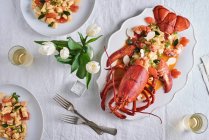 Lobster with rigatoni on a table decorated with a vase of tulips (seen from above) — Stock Photo