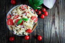 Nudelsalat mit Basilikum, Tomaten, schwarzen Oliven, roten Zwiebeln und Feta-Käse — Stockfoto