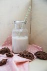 Рослинний напій у скляній пляшці з веганським шоколадним печивом поруч з ним — стокове фото