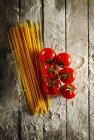 Pomodori ciliegini con spaghetti e farina su un tavolo di legno — Foto stock