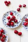 Свежие вишни на тарелках и рядом — стоковое фото