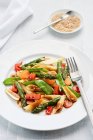 Ensalada de pasta de estilo asiático con espárragos verdes, guisantes azucarados, cebolletas, pimientos rojos y zanahorias - foto de stock