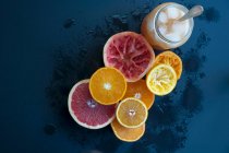 Цитрусові фрукти, деякі з соком вичавлені, і склянка соку з кубиками льоду — стокове фото