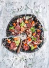 Черная пицца с ветчиной, колбасой, беконом и овощами — стоковое фото