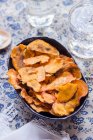 Baked potato chips with honey in a white bowl on an old wooden background. selective focus. - foto de stock
